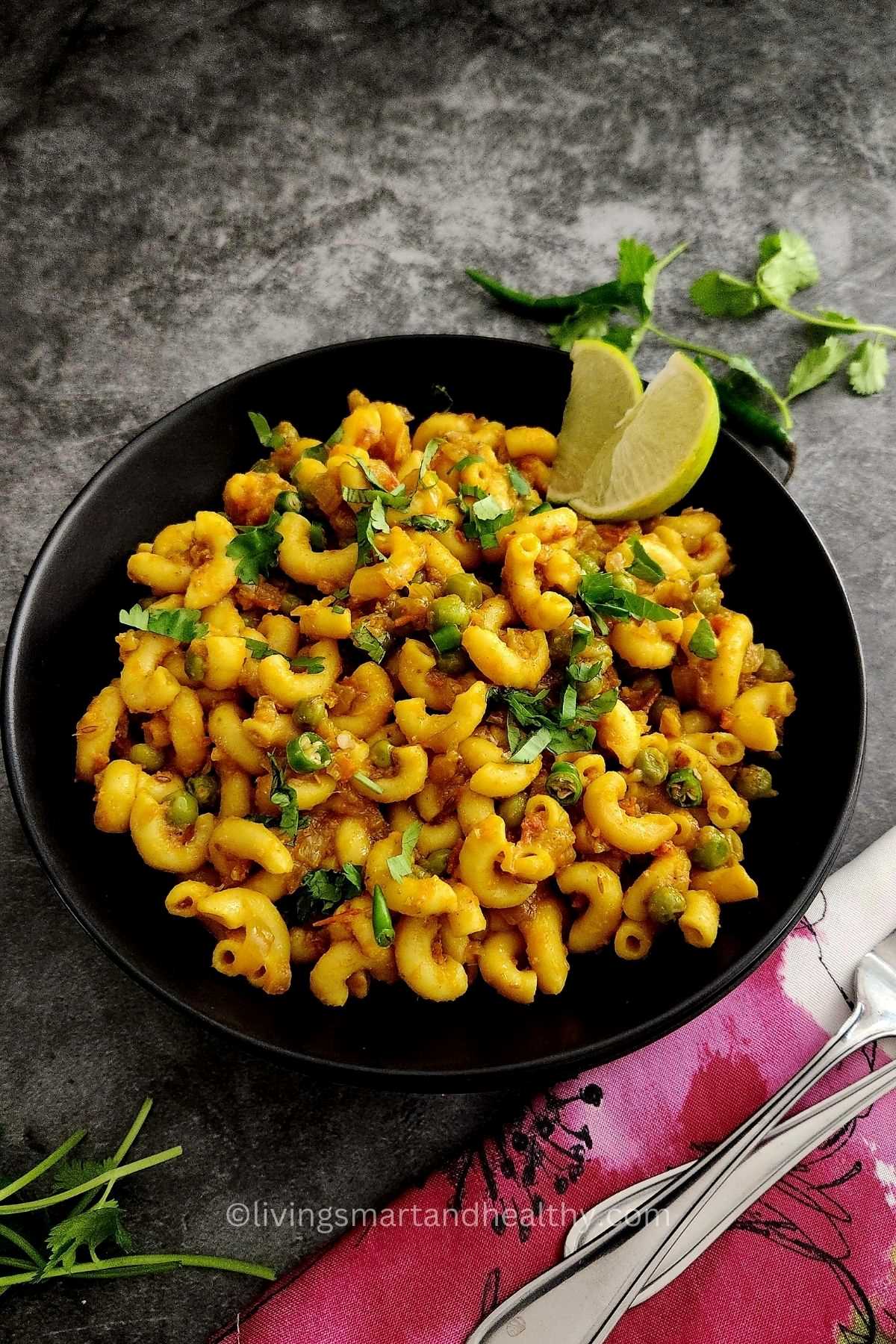 masala macaroni served in a bowl and garnished with lemon wedges
