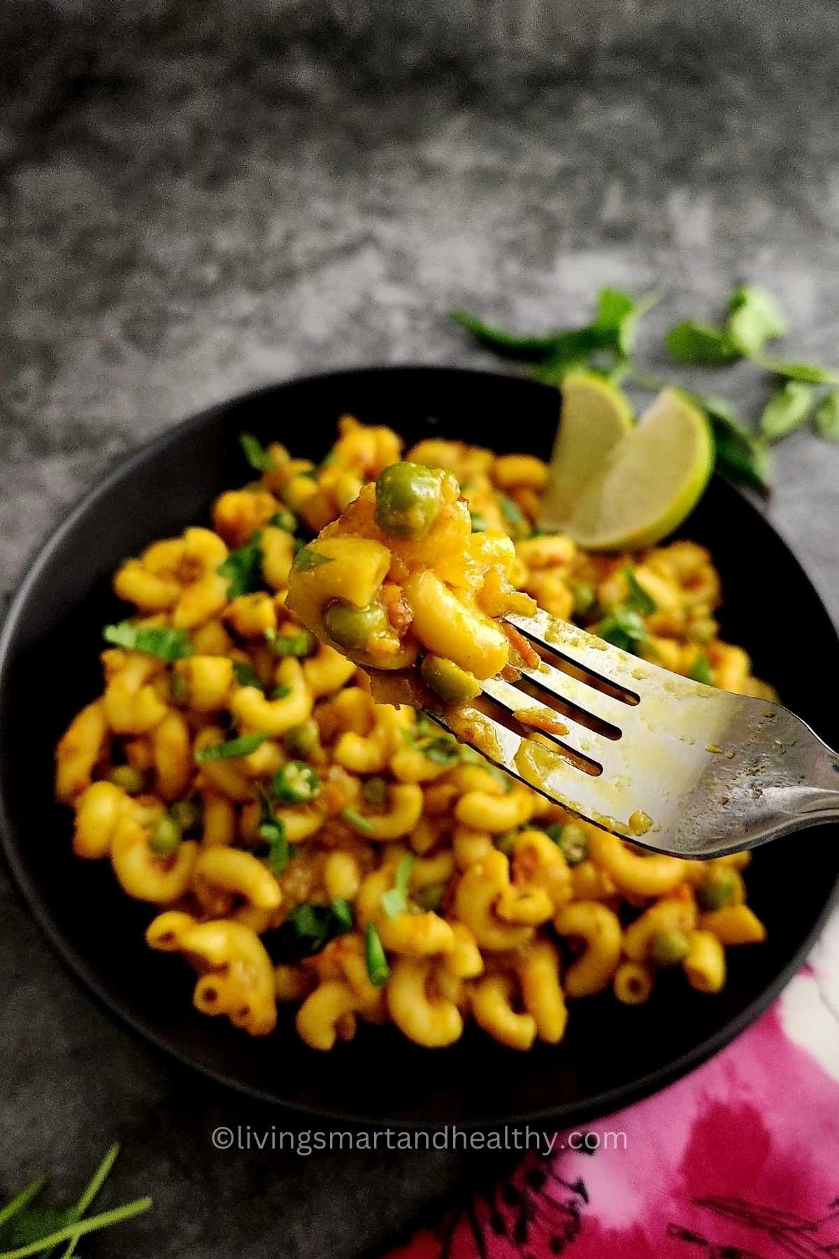 masala macaroni served in a black bowl with fork