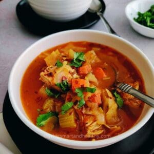 Bowl of homemade chicken and cabbage soup garnished with fresh herbs