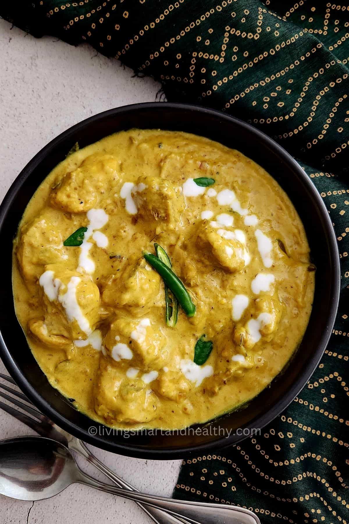 Coconut and chicken curry simmering in a pan with curry leaves and garam masala