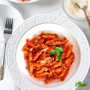 Creamy Instant Pot Penne alla Vodka served in a white bowl topped with fresh basil