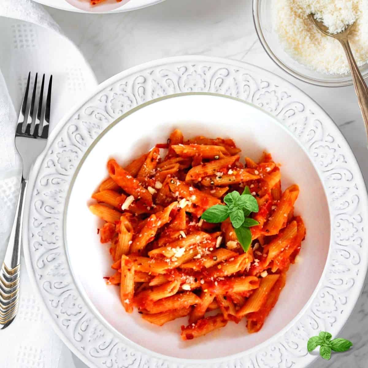 Creamy Instant Pot Penne alla Vodka served in a white bowl topped with fresh basil