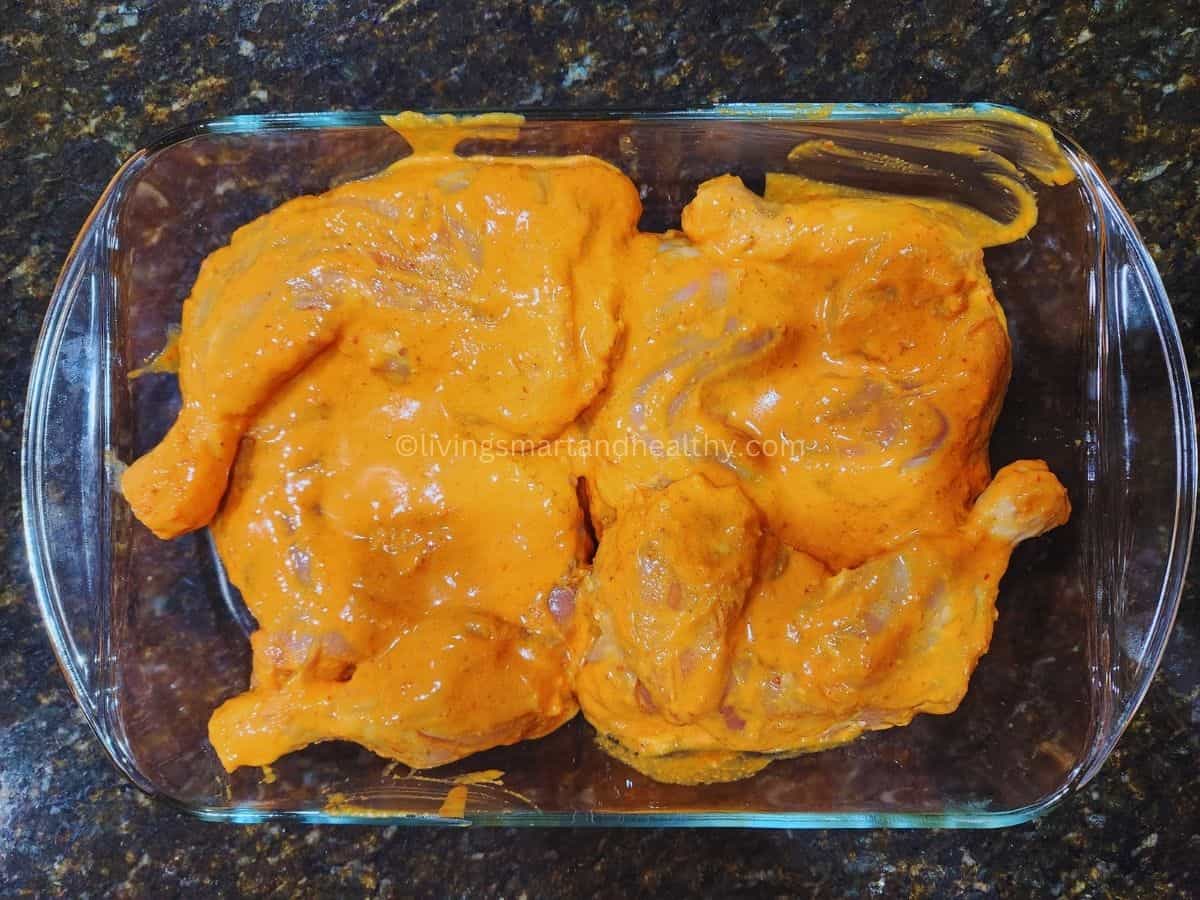 Raw chicken leg quarters marinated in tandoori spices for oven baked tandoori chicken