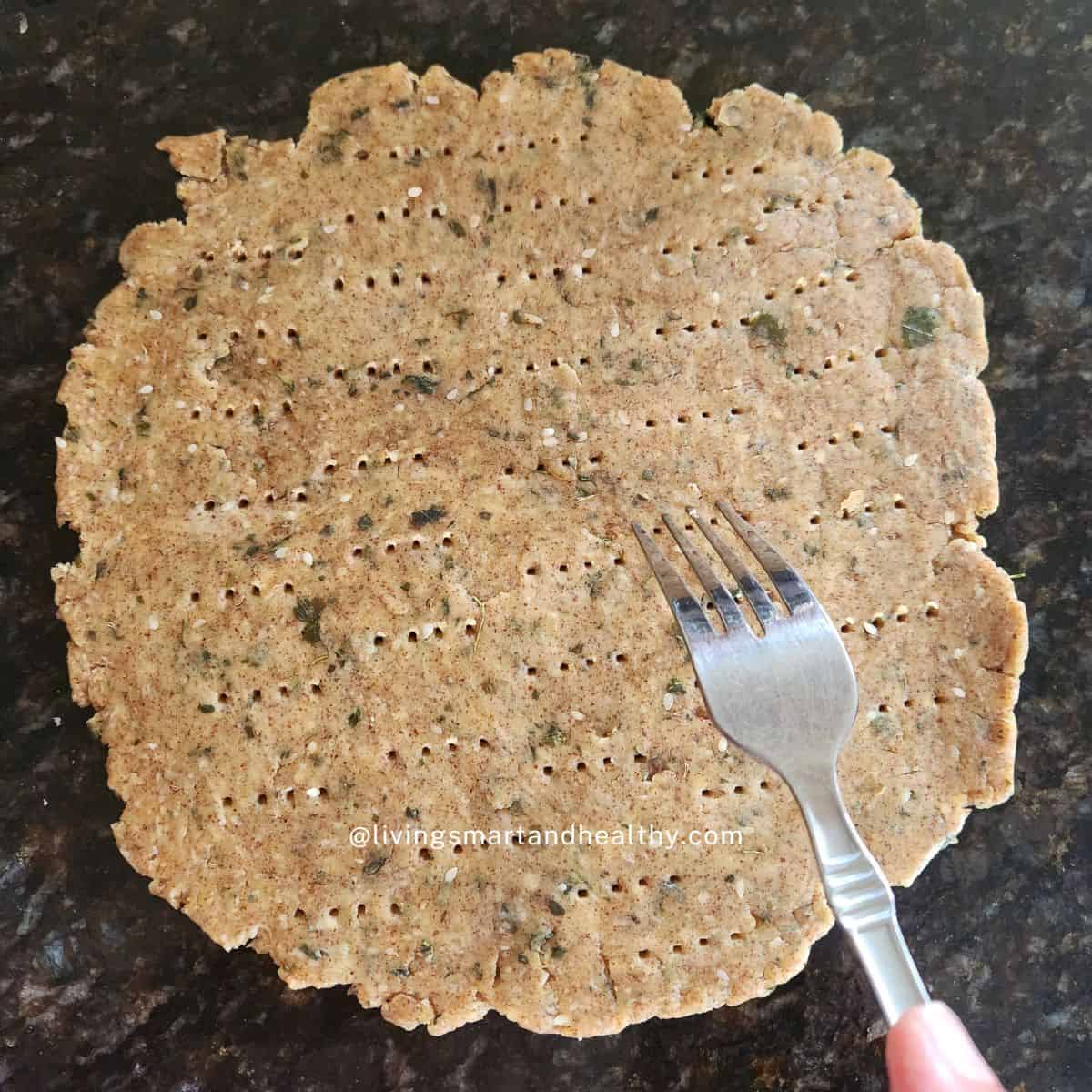Roll the methi mathri dough and pricked with a fork to prevent puffing before baking.