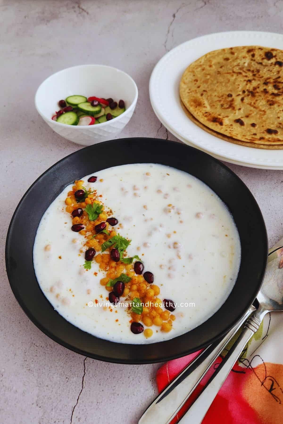 Creamy boondi raita topped with roasted cumin powder, pomegranate seeds and fresh coriander leaves