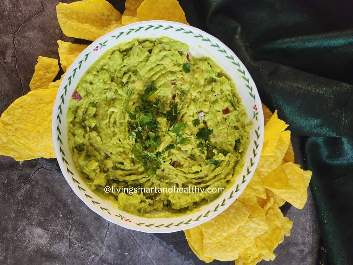 Fresh homemade guacamole in a bowl served with tortilla chips and lime wedges