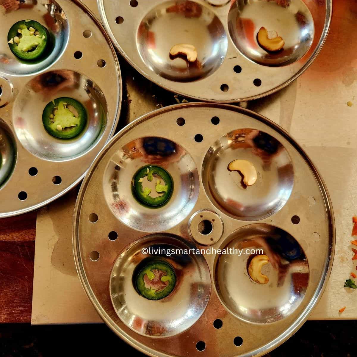 grease the idli mold and place cashews