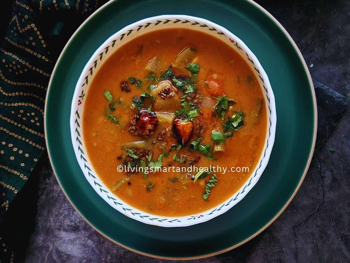 One pot sambar recipe made in Instant Pot with toor dal, drumstick, and mixed vegetables, served in a white bowl