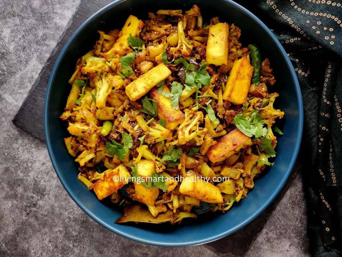 Gobi paneer sabzi in a black iron kadai garnished with fresh coriander leaves