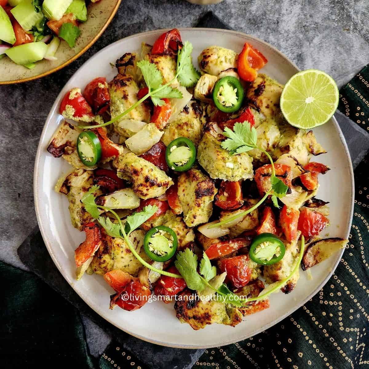 Hariyali chicken tikka kebab served on a platter with sliced onions, lemon wedges, and green chutney