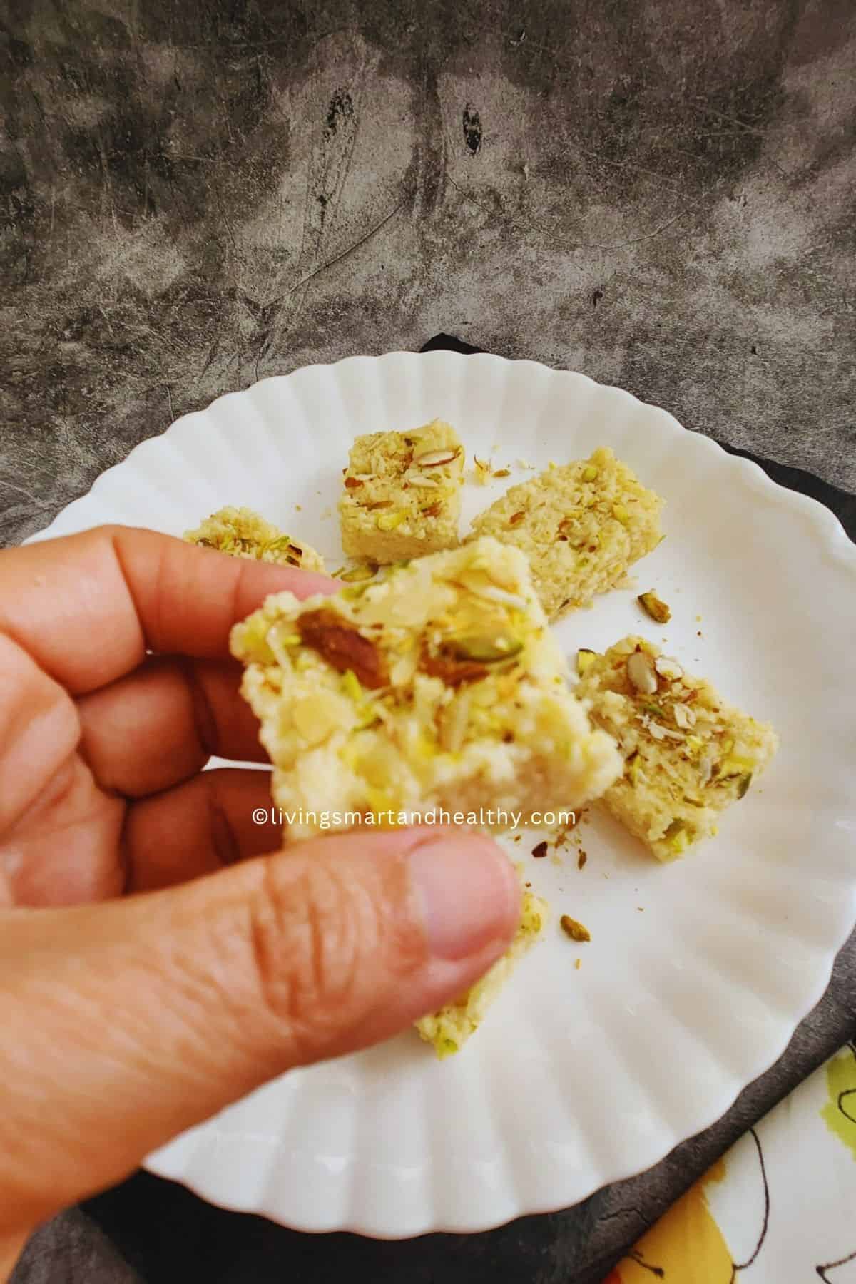 Homemade kalakand with ricotta cheese garnished with chopped pistachios, cut into square pieces.