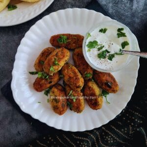 Golden tofu kebab on a plate with green chutney and lemon wedges